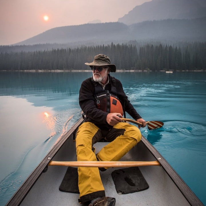 man canoeing on a blue mountain lake