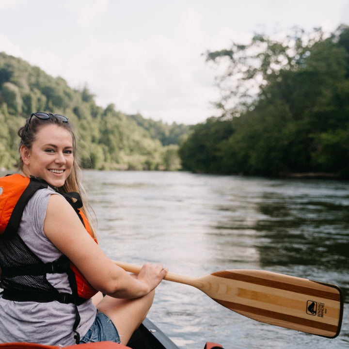 woman looking back while paddling a canoe
